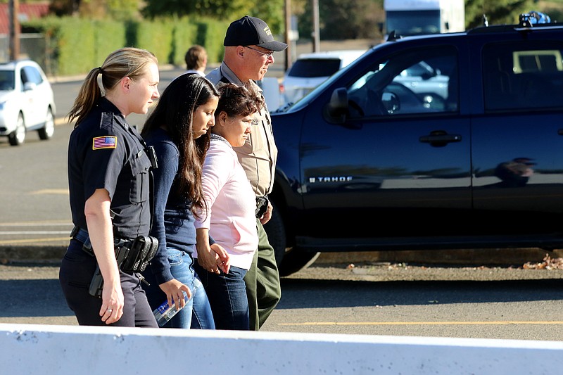 People leave the county fairgrounds in Roseburg, Ore., Thursday, Oct. 1, 2015, following a deadly shooting at nearby Umpqua Community College. Students and faculty were bused to the fairgrounds where counselors were available and some parents waited for their children. 