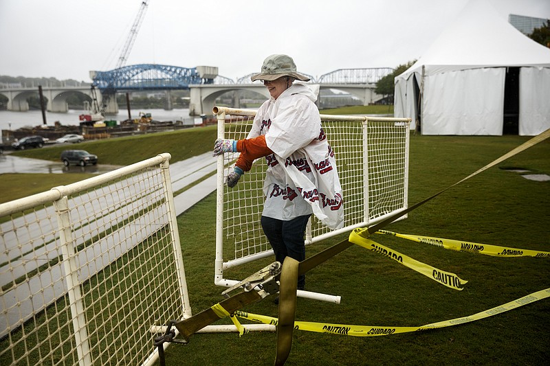 Ann Ball with Chattanooga Presents sets up a fence around the stage in preparation for the 3 Sisters Bluegrass Festival at Ross's Landing amid rainy weather Friday, Oct. 2, 2015, in Chattanooga, Tenn. The festival is set to continue despite inclement weather expected through the weekend.