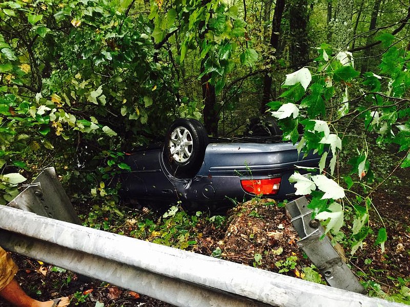 An overturned car rests in the woods at the scene of a crash Friday on Montlake Road.