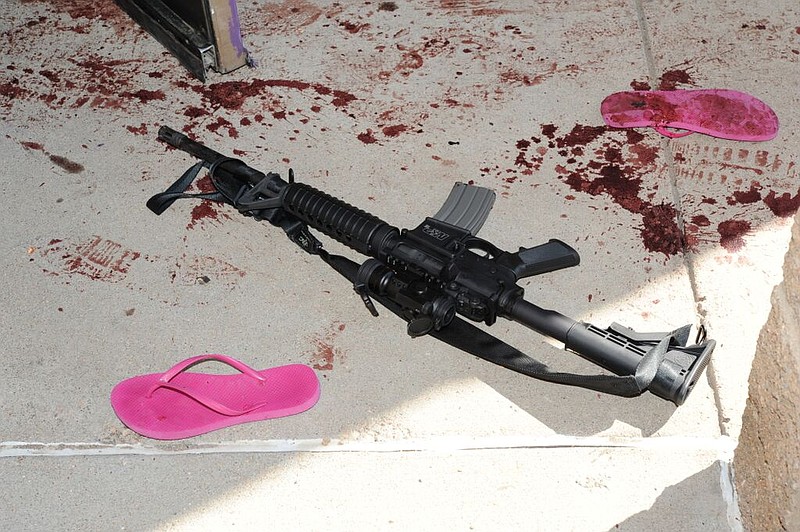 
              FILE - This July 2012 evidence photo provided by the Arapahoe County District Attorney's Office shows an assault weapon and blood by sandals following the July 20, 2012 Colorado theater shooting by James Holmes in Aurora, Colo. More than 400 people were in the theater, and 12 were killed. Another 70 were injured. (Arapahoe County District Attorney's Office via AP)
            
