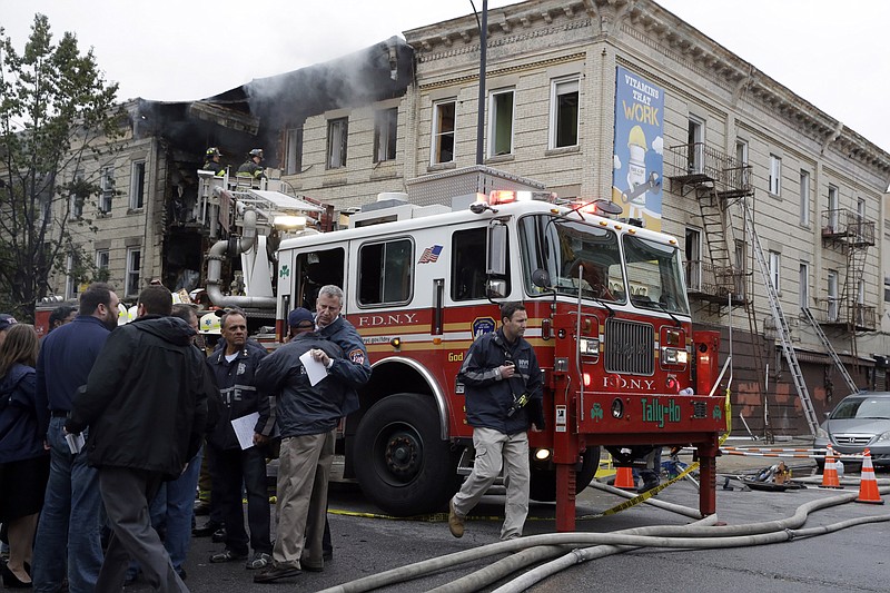 New York City Mayor Bill de Blasio, second from right, hugs Brooklyn Borough President Eric Adams at the scene of a fatal explosion in the Brooklyn borough of New York on Saturday, Oct. 3, 2015. Fire Commissioner Daniel Nigro says the explosion apparently happened after a stove was disconnected.