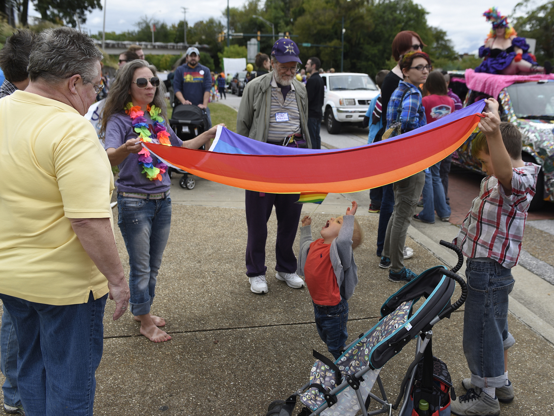 Bentley Combs waves a rainbow flag as he stands underneath a flag held by Tiffany McGee, left, and Ranger Bickford as they wait to participate in the Chattanooga Pride Festival parade on Riverfront Parkway on Sunday, Oct. 4, 2015., in Chattanooga, Tenn.