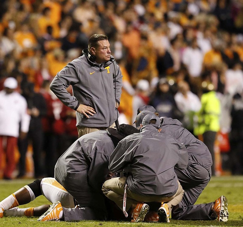 Tennessee coach Butch Jones stands over an injured player during Saturday night's home game against Arkansas.