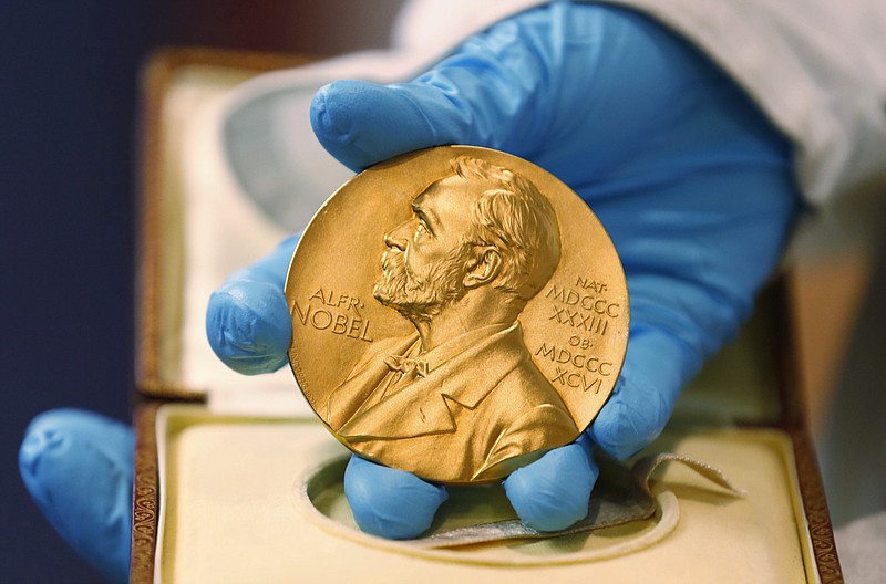 
              FILE- In this file photo dated Friday, April 17, 2015, A national libray employee shows the gold Nobel Prize medal awarded to the late novelist Gabriel Garcia Marquez, in Bogota, Colombia.  The beginning of October 2015 means Nobel Prize time, when committees in Stockholm and Oslo announce the winners of what many consider the most prestigious awards in the world, each worth some 8 million Swedish kronor (US dlrs 960,000) presented to the worthy recipients with a diploma and a gold medal. (AP Photo/Fernando Vergara, FILE)
            