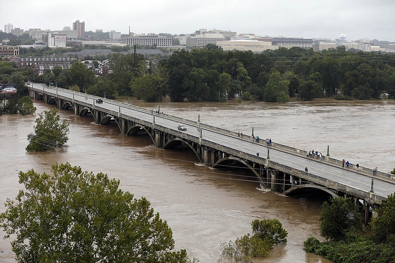 The Congaree River, swollen with floodwaters, flows under the Gervais Street bridge in West Columbia, S.C. in Columbia, S.C., Sunday, Oct. 4, 2015. Hundreds were rescued from fast-moving floodwaters Sunday in South Carolina as days of driving rain hit a dangerous crescendo that buckled buildings and roads, closed a major East Coast interstate route and threatened the drinking water supply for the capital city.