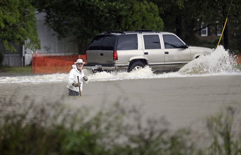 
              Floodwaters rise as a vehicle and a man navigate flooded streets in Florence, S.C., Sunday, Oct. 4, 2015. The rainstorm drenching the East Coast brought more misery Sunday to South Carolina, cutting power to thousands, forcing hundreds of water rescues and closing scores of roads because of floodwaters. (AP Photo/Gerry Broome)
            