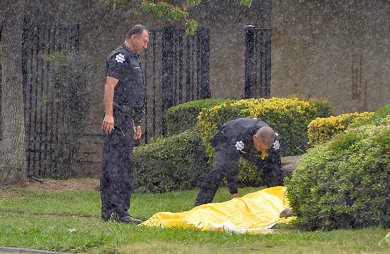 
              In this Thursday, Oct. 1, 2015 photo, Fresno Police officers cover the body of a person after two were fatally shot at North San Pablo Avenue and East Barstow Avenue in Fresno, Calif. Fresno police identified deceased as brothers as Willie Ford, 19, and Denzel Ford, 18. A third brother, 17-year-old Benzo Ford, died July 12 when a bullet fired from a nearby alley came through a window into a bedroom. Police say they believe he was targeted. (Silvia Flores/The Fresno Bee via AP)
            
