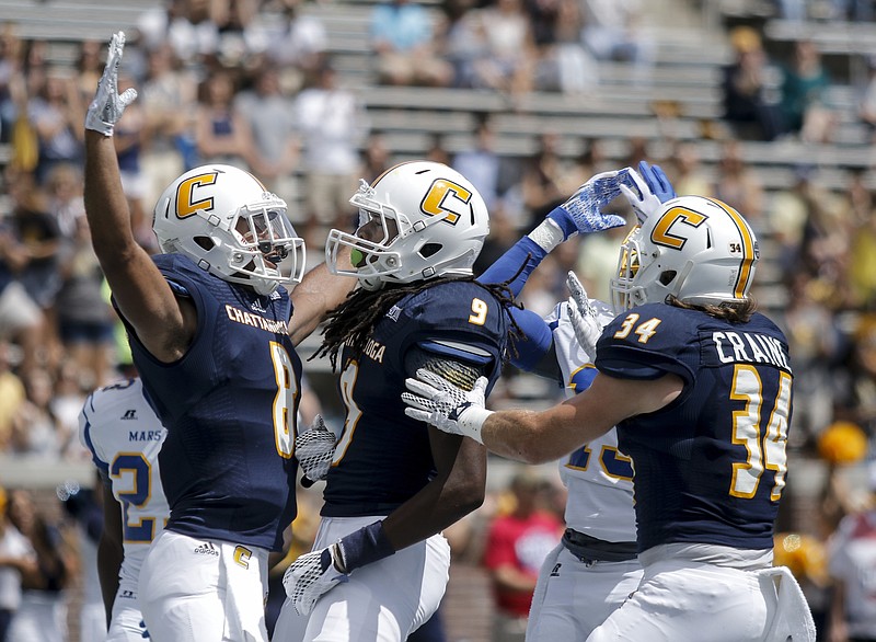 UTC teammates C.J. Board, Alphonso Stewart, and Derrick Craine, from left, celebrate a touchdown during the Mocs' football game against the Mars Hill Lions at Finley Stadium on Saturday, Sept. 12, 2015, in Chattanooga. UTC won 44-34.