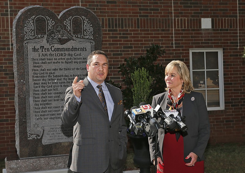 
              Oklahoma Gov. Mary Fallin, right, looks on as Michael Carnuccio, left, president of the Oklahoma Council of Public Affairs, speaks, during a news conference in Oklahoma City, Tuesday, Oct. 6, 2015. The controversial Ten Commandments monument has been moved from the state Capitol to the grounds of the private OCPA campus. Fallin said she would work with lawmakers for a  Constitutional amendment to allow the monument to return to the state Capitol. (AP Photo/Sue Ogrocki)
            