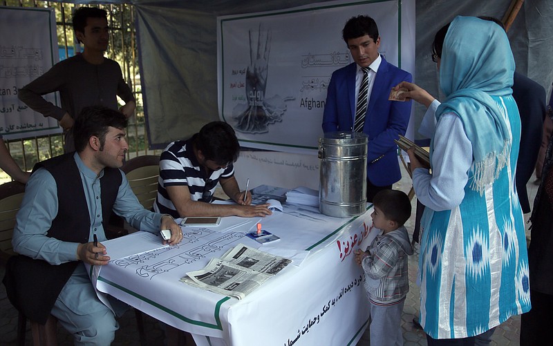 
              A woman donates money at a tent of the Afghanistan 3rd Trend, a civil organization to help displaced people from Kunduz, as its staff members work in Kabul, Afghanistan, Monday, Oct. 5, 2015. Mohammad Omer Safi, the sacked former governor of Kunduz, whose capital city was seized by the Taliban last week, said Monday that he repeatedly warned the government that Kunduz was vulnerable to attack and that his appeals to beef up protection fell on deaf ears, deepening concerns that the Afghan leadership failed to act until it was too late. (AP Photo/Massoud Hossaini)
            