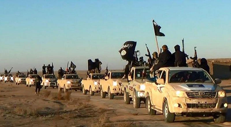 
              FILE - In this undated file photo released by a militant website, which has been verified and is consistent with other AP reporting, militants of the Islamic State group hold up their weapons and wave flags as they ride in a convoy, which includes multiple Toyota pickup trucks, through Raqqa city in Syria on a road leading to Iraq. Toyota is working with U.S. officials after questions were raised about the prominent use of its vehicles by militant organizations in Syria, Iraq and Libya. (Militant website via AP, File)
            