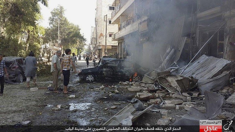 
              In this Monday, Oct. 5, 2015 photo released by the Rased News Network, a Facebook account affiliated with Islamic State militants, which has been authenticated based on its contents and other AP reporting, people gather at the site of an airstrike in Al-Bab on the outskirts of Aleppo, Syria. The Britain-based Syrian Observatory for Human rights said warplanes believed to be Russian have targeted the northern town of Al-Bab that is a stronghold of the Islamic State group. The Arabic at the bottom reads, "The destruction that was caused by airstrikes of the Crusader-Alawite coalition on the town of Al-Bab." (Rased News Network via AP)
            