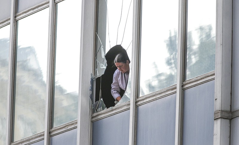 Atlanta police investigator Sergeant L. Lacoss measures the broken window at building where a handcuffed man jumped through a third-floor window Tuesday morning, Oct. 6, 2015, in downtown Atlanta to avoid arrest. 