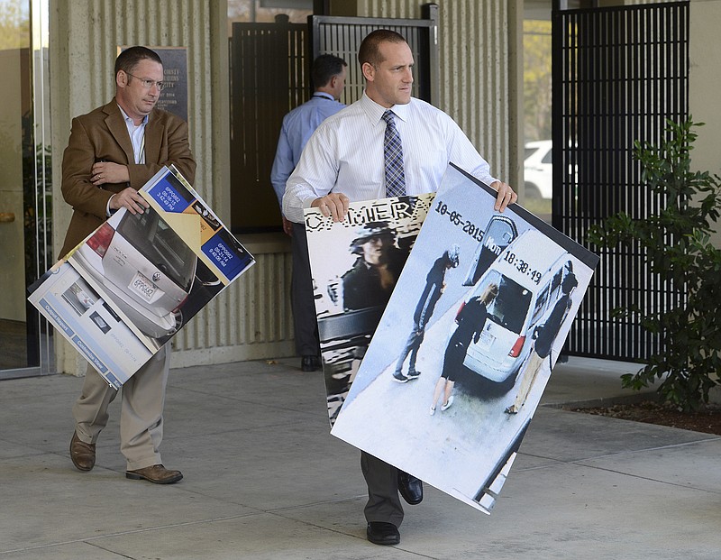 Marin County Sheriff's department personnel carry security camera photos before a news conference regarding the death of 67-year-old yoga teacher Steve Carter, in San Rafael, Calif., Wednesday, Oct. 7, 2015. Three people have been arrested in the killing of a California yoga teacher who was shot on a trail in what appeared to be a random crime while walking his dog, authorities said Wednesday.
