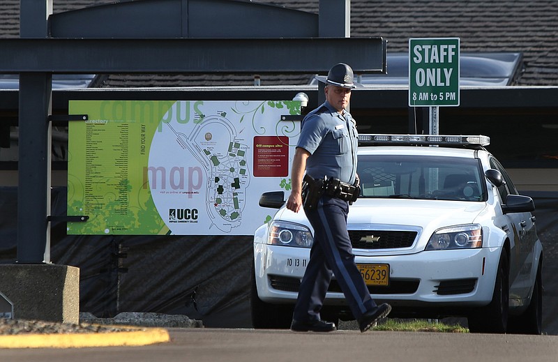 An Oregon State Patrol Trooper walks the grounds of Umpqua Community College near Roseburg, Ore.