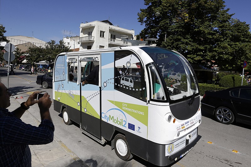 
              FOR STORY GREECE DRIVERLESS BUS BY DEREK GATOPOULOS - In this photo taken on Tuesday, Oct. 6, 2015, a local resident takes a photo of the tiny CityMobil2 driverless bus in Trikala town, Greece. Trials of the French-built CityMobil2 buses have started in Trikala, a town of some 80,000 people, chosen to test a driverless bus in real traffic conditions for the first time, as part of a European project to revolutionize mass transport, guided by GPS, lasers, and wireless cameras, and the rides are free. (AP Photo/Thanassis Stavrakis)
            