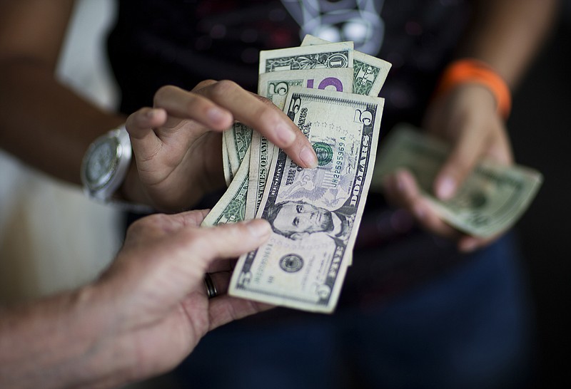 
              FILE - In this June 6, 2015, file photo, a customer, bottom, pays for goods while shopping at the Atlanta Farmers Market in Atlanta. Americans will spend at a slower pace than last year during the crucial winter holidays because of sluggish wage growth and other factors, the largest U.S. retail trade group said, Thursday, Oct. 8, 2015. (AP Photo/David Goldman, File)
            