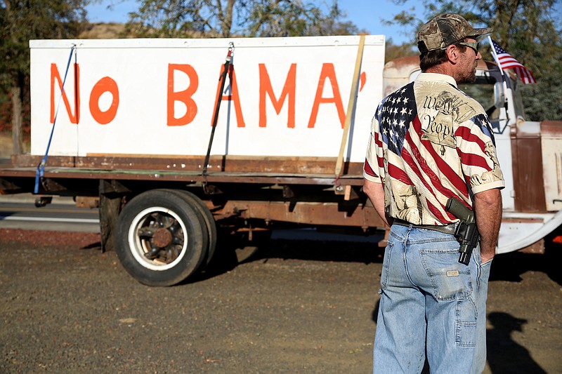 
              Michael Johnson waits outside of Roseburg Municipal Airport for President Barack Obama's arrival in Roseburg, Ore., Friday, Oct. 9, 2015. Gun-rights activists say they plan to protest when Obama visits here Friday to meet with families of victims of last week's college shooting rampage. They are angry about Obama's call for more gun restrictions after the killing of eight students and a teacher. (AP Photo/Ryan Kang)
            