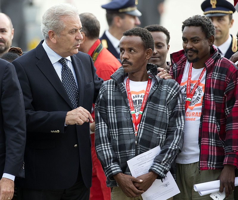 
              European Commissioner for Migration and Home Affairs Dimitris Avramopoulos, left, speaks to Eritrean refugees waiting to board an Italian Financial police aircraft which will take them to Sweden, at Rome's Ciampino airport, Friday, Oct. 9, 2015. The aircraft, carrying 19 Eritreans, will bring the first refugees to Sweden under the European Union's new resettlement program aimed at redistributing asylum-seekers from hard-hit receiving countries. (AP Photo/Andrew Medichini)
            