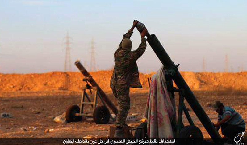 
              In this image posted on Thursday, Oct. 8, 2015, by the Rased News Network, a Facebook page affiliated with Islamic State, shows Islamic State militants preparing to fire a mortar to shell towards Syrian government forces positions at Tal Arn in Aleppo province, Syria. Islamic State militants seized several villages from rival insurgents north of Aleppo city Friday, in a surprise attack that came despite intensive Russian airstrikes that Moscow insists are targeting the extremist group, activists said. Arabic reads, "Targeting positions of the Alawite army in Tal Arn with mortar shells." (Islamic State militant website via AP)
            