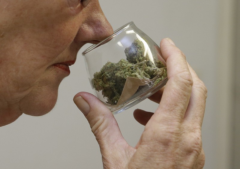 In this Aug. 19, 2015 file photo, a customer checks the aroma of a jar of medicinal marijuana at Canna Care, a medical marijuana dispensary in Sacramento, Calif. Gov. Jerry Brown signed a trio of bills, Friday, Oct. 9, 2015, that created the first statewide licensing and operating rules for pot growers, manufacturers of cannabis-infused products and retail weed outlets.