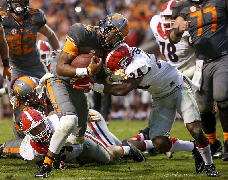 Tennessee quarterback Joshua Dobbs, left, puts his shoulder into Georgia safety Dominick Sanders to power into a touchdown run during their SEC football game at Neyland Stadium on Saturday, Oct. 10, 2015, in Knoxville, Tenn. Tennessee won 38-31.