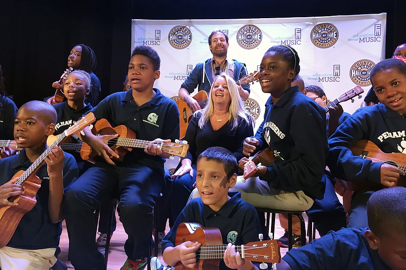 
              In this Oct. 5, 2015 photo, Liz Rose, center, a Grammy-award winning country music songwriter from Nashville, rehearses a song with students at Pelham Gardens Middle School in the Bronx borough of New York. Rose is working with the students through a program funded by the Country Music Association Foundation which provides a curriculum for teachers to develop language skills through the art of songwriting. (AP Photo/William Mathis)
            