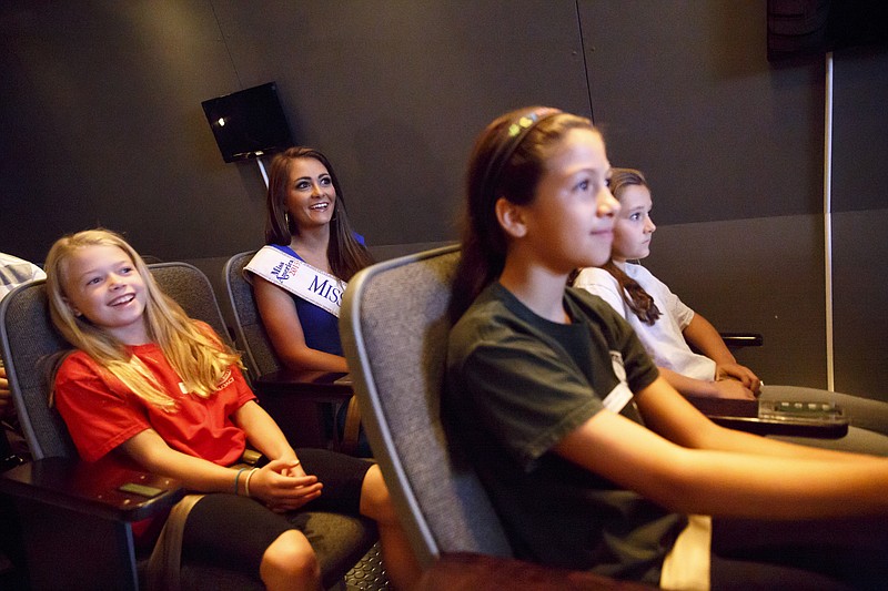 Miss Tennessee Hannah Robison, center, sits in the shuttle simulator with students Whitney Sanders, left, Grace Moore, right, and Gabby Land at the Challenger STEM Center on Tuesday, Oct. 13, 2015, in Chattanooga, Tenn. Robison, a chemistry major who has been working to promote STEM education since she was crowned in June, joined students from Harding Academy in Nashville on their trip to the center.