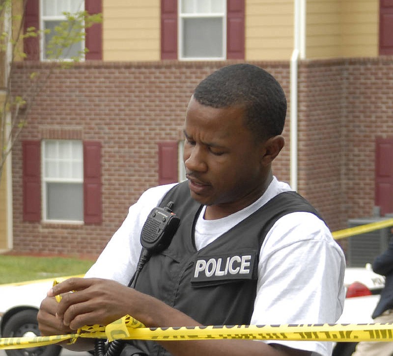 Investigator Robin Davenport tie up crime-scene tape at the scene of a shooting in 2008.