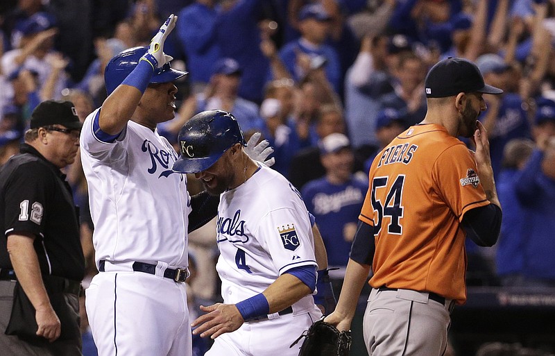 Kansas City Royals' Alex Gordon, center, and Salvador Perez, left, celebrate in front of Houston Astros pitcher Mike Fiers, right, after scoring on a double by teammate Alex Rios during the fifth inning of Game 5 in baseball's American League Division Series, Wednesday, Oct. 14, 2015, in Kansas City, Mo. 
