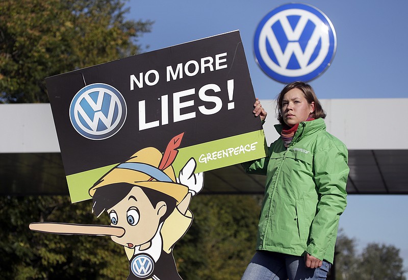 An activist holds a protest poster in front of a factory gate of the German car manufacturer Volkswagen in Wolfsburg, Germany.
