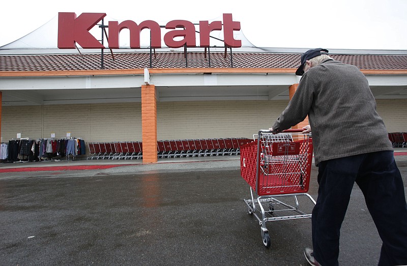 A customer pushes a shopping cart outside a Kmart store. Three local Kmarts will soon close as the store scales back nationwide. (AP Photo/Paul Sakuma, File)
            
