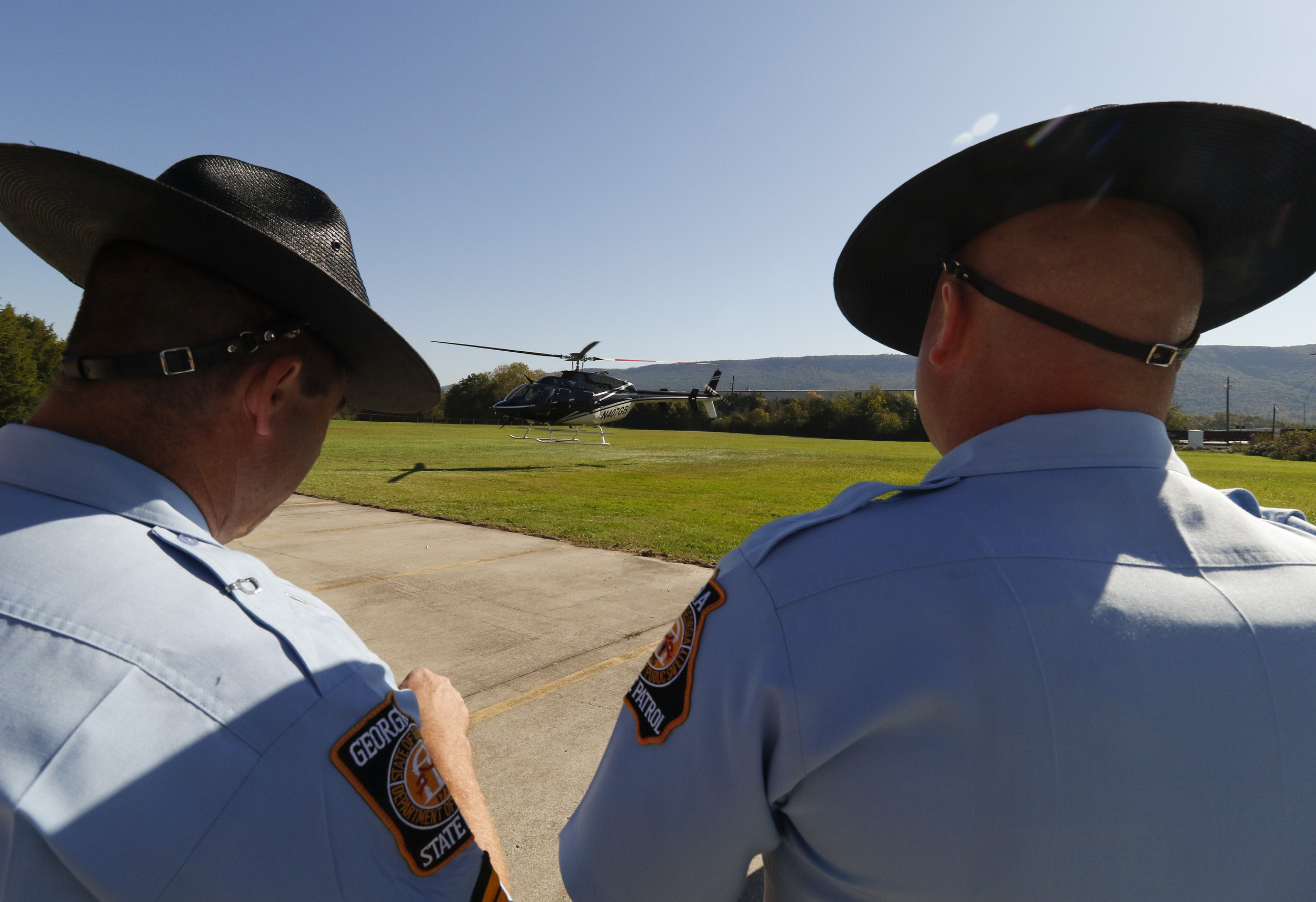 Staff Photo by Dan Henry / The Chattanooga Times Free Press- 10/15/15. Troopers watch as Georgia Governor Nathan Deal boards a helicopter after speaking on Thursday, October 15, 2015 to officials and guests on the new Vanguard site in Trenton during an announcement that the Semi-trailer manufacturing plant is bringing 400 jobs to Dade County.