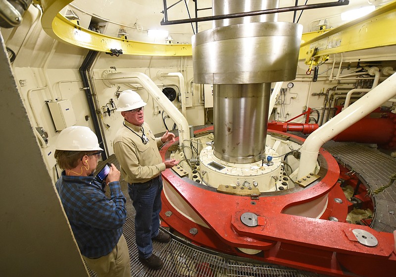 Standing next to one of the four turbine shafts inside the Tennessee Valley Authority's Raccoon Mountain Pumped Storage Facility, Ken Cornett talks about the need for draining the 500-acre reservoir to complete repairs and updates on Friday.plant manager. TVA spokesman Scott Fielder, left, listens to the explanation by Cornett some 1,100 feet underground.
