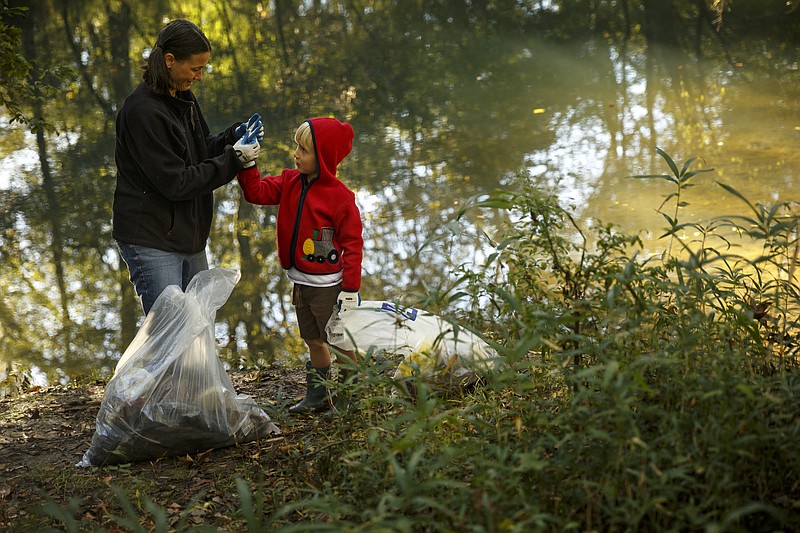 Christy Tittsworth, left, helps fix Luke Sammer's protective glove as they pick up trash around North Chickamauga Creek as part of the Tennessee River Rescue on Saturday, Oct. 17, 2015, in Hixson, Tenn. The annual river rescue, which takes place across three counties, was started by volunteers to keep the Tennessee river and its tributaries clean.
