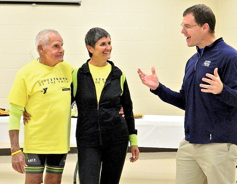 Tom and Pat Cawood, left, who recently cycled from San Diego, Calif., to St. Augustine, Fla., receive congratulations from Matt Ryerson, president and CEO of United Way of Bradley County, during an YMCA Cleveland event commemorating their 3,070-mile cross county journey. Ryerson, who said he met the couple while teaching a course on nonprofit operations and considers them as friends, presented them with a bicycle wheel, right, decorated in trip photos to hang in their home.