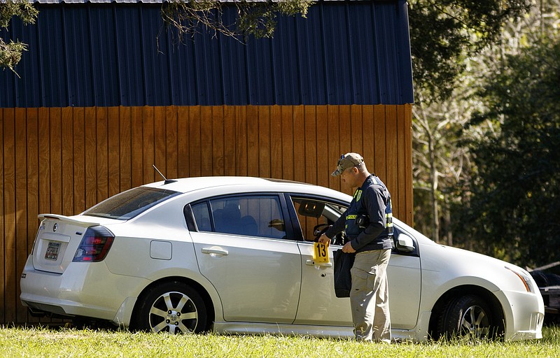 An GBI crime scene investigator hangs an evidence marker above a bullet hole in a car door as he works the scene of a shooting that took place Monday night at 1249 Straight Gut Road on Tuesday, Oct. 20, 2015, in Rock Spring, Ga. Michael James Gobert has been charged with one count of murder and two counts of aggravated assault after the Walker County Sheriff's Department says he opened fire with a handgun on a vehicle occupied by Johnny "J.J." Montgomery, Edrius J. Putman, and Deisman Harrison, killing Montgomery and injuring Putman in the leg.