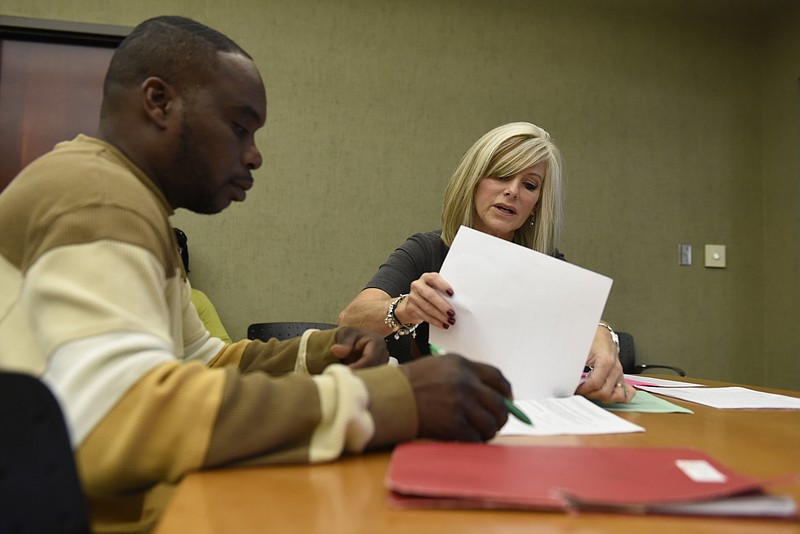 Theresa Biggs, housing coordinator at the Chattanooga Housing Authority, helps Aaron McCrary with his paperwork at the agency's offices on Wednesday, Oct. 14, 2015, in Chattanooga, Tenn. Her role is to help people with housing vouchers navigate the system and connect with affordable housing. 