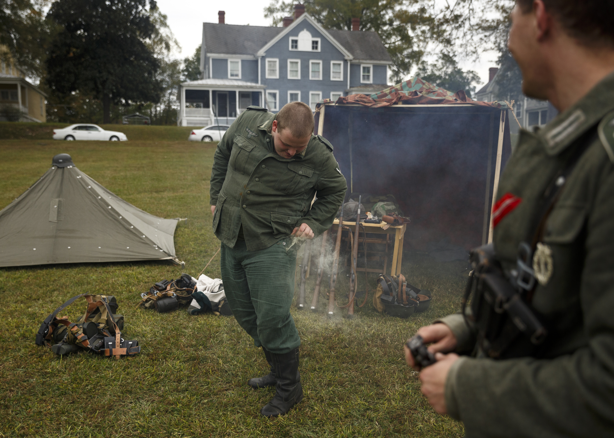 Tyler Stanton checks his left pocket after a fellow re-enactor placed a smoke grenade in it in the German camp at the 6th Cavalry Museum's 6th annual Remembering Our Heroes event on Saturday, Oct. 24, 2015, in Fort Oglethorpe, Ga. The event featured one World War II battle re-enactment, but the second re-enactment was changed to a firing demonstration after lower spectator turnout.