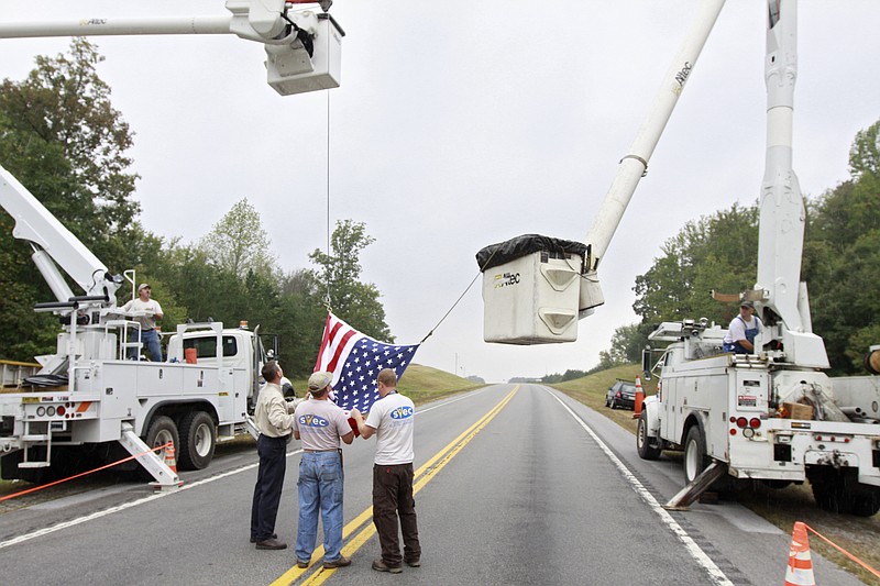Sequachee Valley Electric Cooperative employees raise a flag over State Highway 108 for a veteran's funeral in this 2011 photo. Controversy has arisen over a little-known law that gives electric co-ops like SVEC property tax breaks for investments in plants and facilities.