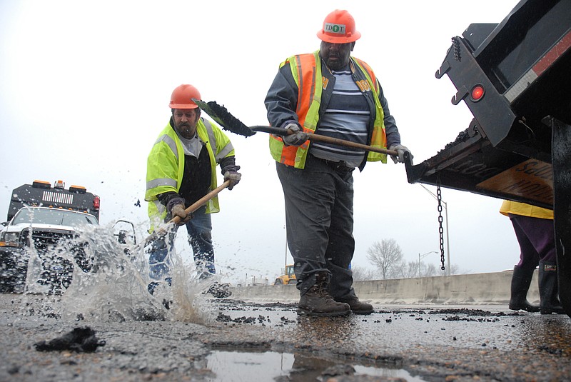 Jeff Moore, left, and Willy Moore, with Tennessee Department of Transportation, fill a pothole near the Rossville Avenue exits downtown along Highway 24 going eastbound.