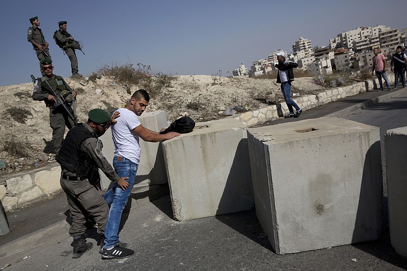 
              FILE - In this Thursday, Oct. 15, 2015 file photo, Israeli border police search a Palestinian, next to newly placed concrete blocks in an east Jerusalem neighborhood. An Israeli proposal that would potentially strip tens of thousands of Palestinians in Jerusalem of their residency rights has sent shudders through the targeted Arab neighborhoods _ areas that were dumped outside Israel's separation barrier a decade ago, even though they're within the city's boundaries. The government's review of this plan underscores the fragile status of Palestinians in a city where they have long suffered discrimination and have no citizenship.(AP Photo/Oded Balilty, File)
            