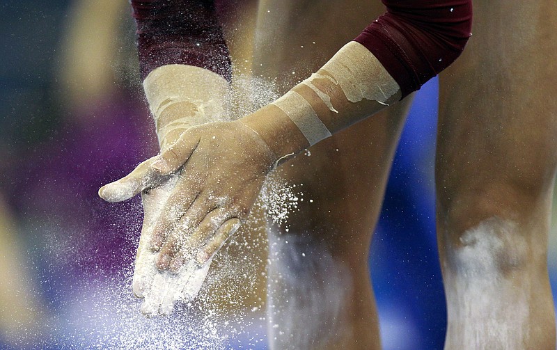 In this 2012 file photo, a gymnast chalks her hands before competing during the semifinals of the NCAA women's gymnastics championships in Duluth, Ga.