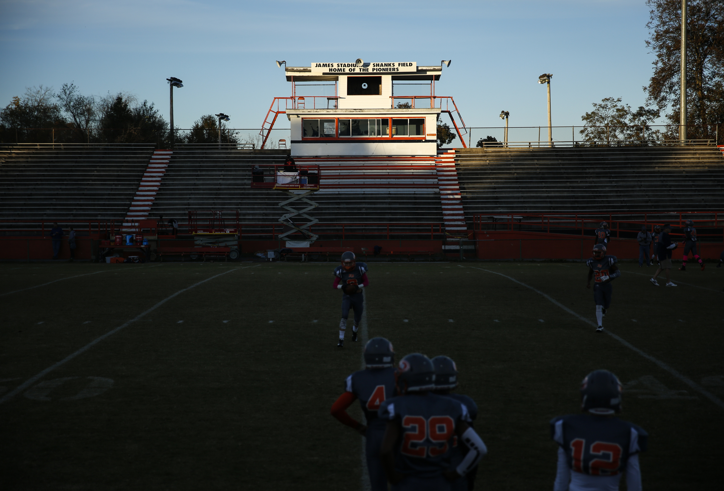 The condemned Raymond James Stadium of East Ridge High School looms behind as players warm up for their prep football game against CCS at East Ridge High School on Friday, Oct. 30, 2015, in East Ridge, Tenn.