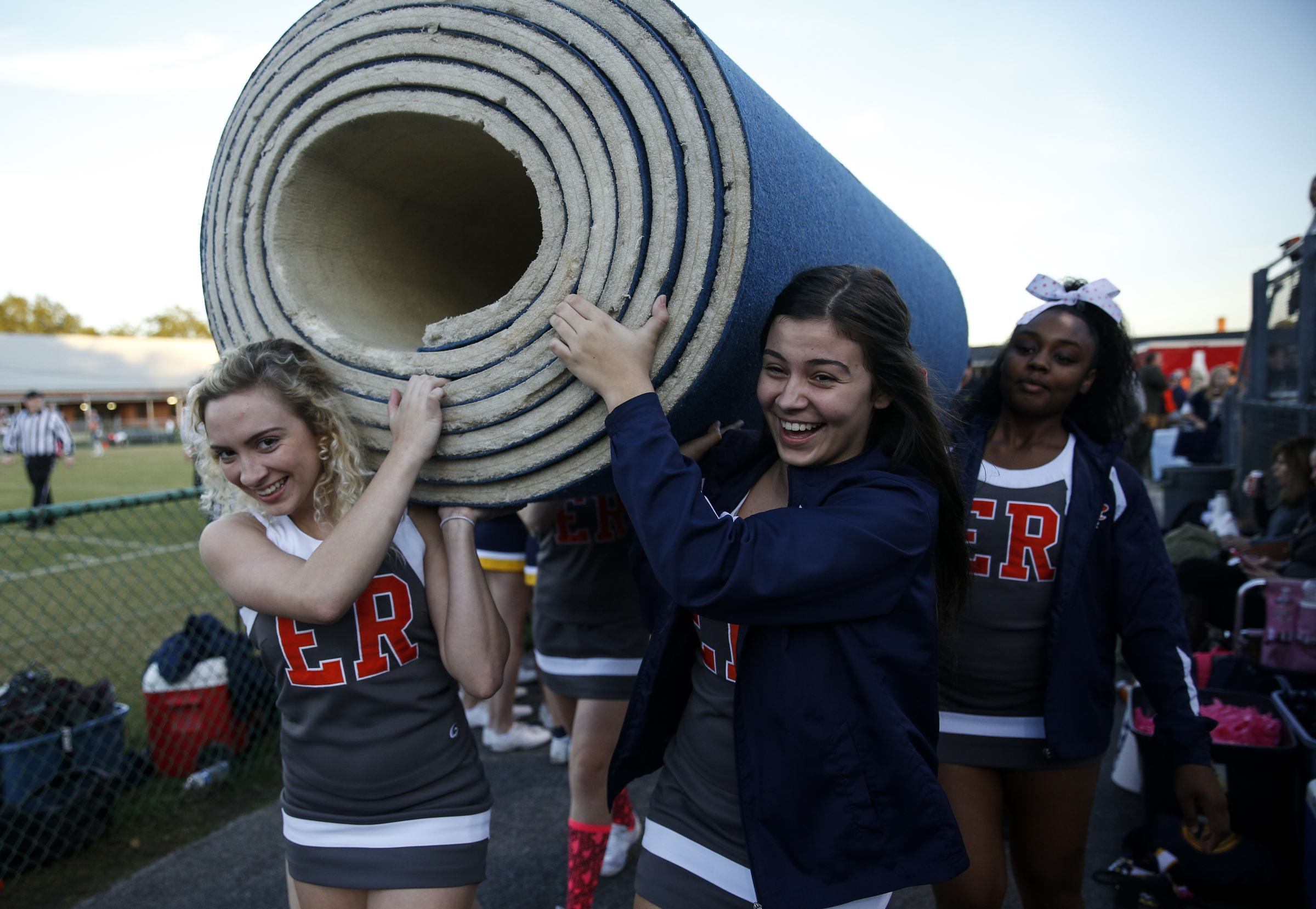 East Ridge cheerleaders Maeghan Owens, Lejla Dukic, and Abryia Green, from left, carry a tumbling mat to their spot before their prep football game against CCS at East Ridge High School on Friday, Oct. 30, 2015, in East Ridge, Tenn.