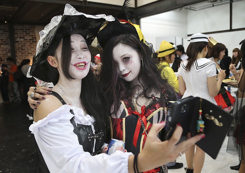 
              In this Oct. 24, 2015 photo, Aya Shiozaki, left, and Shoko Ushimaru pose for a photo during a Halloween party event in Tokyo. The spooky celebration is consuming the energy, fashion sense and wallets of people for the entire month of October, not just kids but also adults on the prowl with colorful parades, costume parties and pumpkin-inspired desserts, dress-up and decor everywhere. (AP Photo/Koji Sasahara)
            