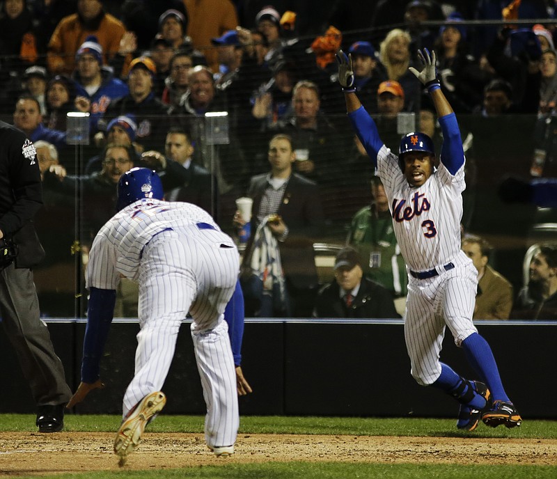 New York Mets' Curtis Granderson (3) cheers as Juan Lagares (12) dives at home plate to score on an RBI single by Juan Uribe during the sixth inning of Game 3 of the Major League Baseball World Series Friday, Oct. 30, 2015, in New York. 