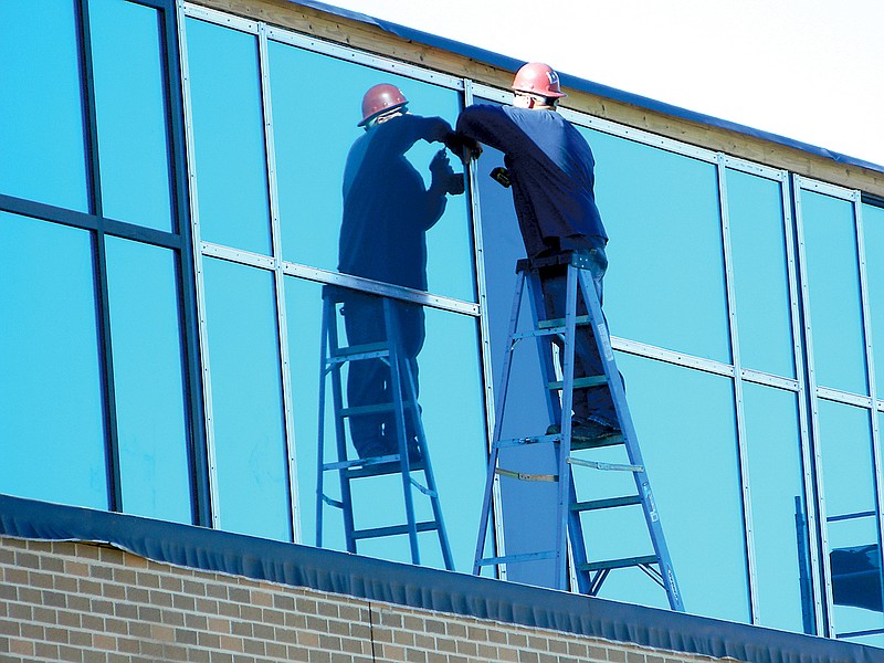 A construction worker attaches exterior framing to the upper windows of Cleveland High School's Raider Arena. The facility, which is projected to be operational next spring, replaces the high school's landmark Raider Dome.