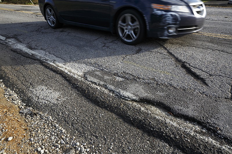 A car drives past cracks visible on the surface of Boy Scout Road on Tuesday, Nov. 3, 2015, in Chattanooga, Tenn. Major improvements to the road are set to begin next week.