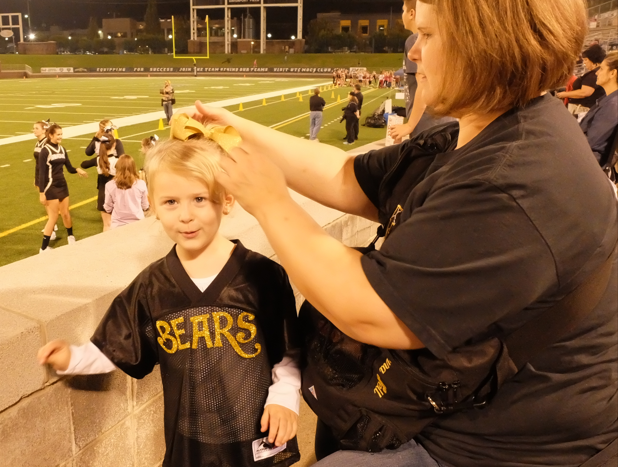 Illiana Blalock, 3, sports a "Bears" shirt as Renee Blalock secures a bow in her hair before the Bradley Central first-round prep football playoff game at Finley Stadium Thursday night.